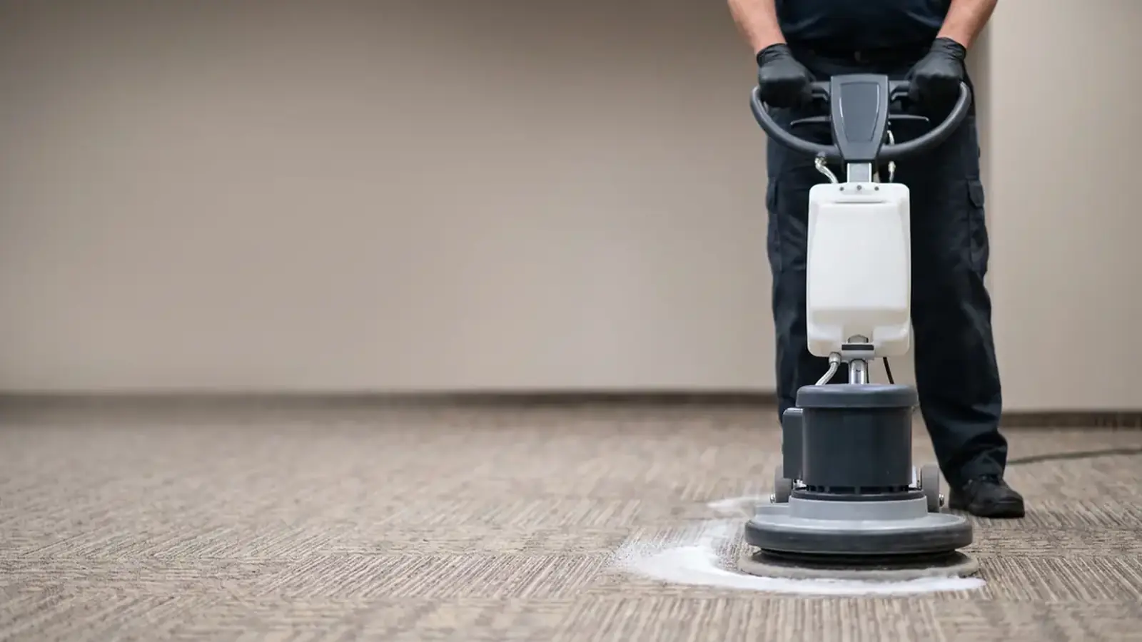 Low-moisture carpet cleaning machine treating a commercial carpet